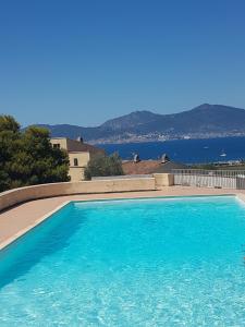 a blue swimming pool with a view of the water at Porticcio avec Piscine proche plage in Porticcio