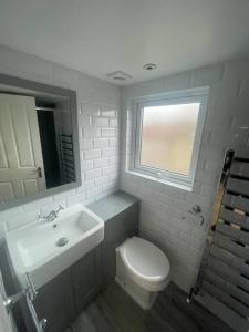 a bathroom with a toilet and a sink and a window at Charming 5 Bed - Leytonstone E11 in London