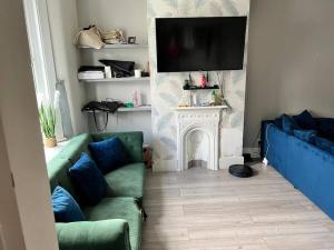 sala de estar con sofá, TV y chimenea en Charming 5 Bed - Leytonstone E11, en Londres