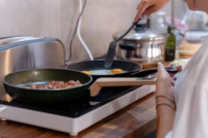 a woman is cooking food in a pan on a stove at Ocean Nomads Coworking in Arona