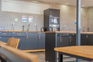 a kitchen with blue cabinets and a microwave and a table at Ocean Nomads Coworking in Arona