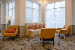 una sala de espera con sillas, sofá y ventanas en Hilton Garden Inn Folsom, en Folsom