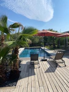 una terrazza in legno con 2 sedie e una piscina di Maison proche du pic Saint Loup a Saint-Jean-de-Cuculles