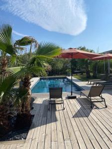 a wooden deck with two chairs and a swimming pool at Maison proche du pic Saint Loup in Saint-Jean-de-Cuculles