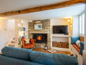 a living room with a blue couch and a fireplace at The Roost at Coln in Coln Saint Aldwyn