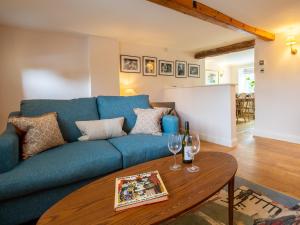 uma sala de estar com um sofá azul e uma mesa em The Roost at Coln em Coln Saint Aldwyn