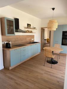 a kitchen with blue cabinets and a table with chairs at Maison proche du pic Saint Loup in Saint-Jean-de-Cuculles