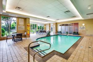 uma piscina no átrio do hotel com uma mesa e cadeiras em Hilton Garden Inn Louisville Airport em Louisville