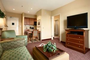 Homewood Suites by Hilton Decatur-Forsyth في Forsyth: غرفة معيشة مع أريكة وتلفزيون بشاشة مسطحة