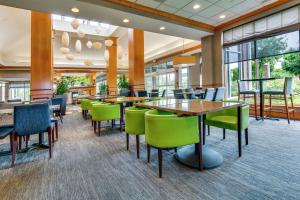 Hilton Garden Inn Louisville Airport في لويزفيل: غرفة طعام مع طاولات وكراسي خضراء