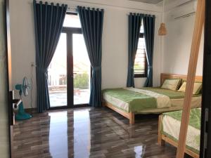a bedroom with two beds and a sliding glass door at Xuka Homestay in Hue