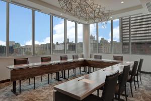 Homewood Suites By Hilton Montreal Downtown في مونتريال: قاعة اجتماعات مع طاولات وكراسي ونوافذ كبيرة