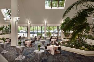 un restaurante con mesas, sillas y palmeras en DoubleTree by Hilton Minneapolis Park Place, en Saint Louis Park