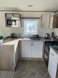 a small kitchen with white cabinets and a sink at luxury caravan in Tattershall