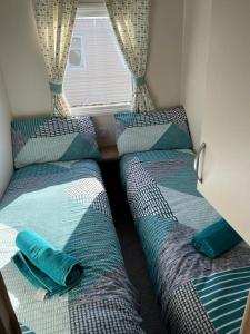 a bedroom with three beds and a window at luxury caravan in Tattershall