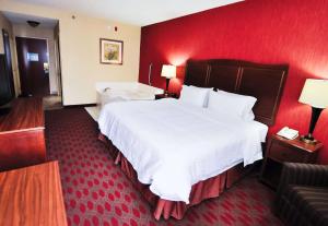 a hotel room with a large bed and a red wall at Hampton Inn Carrollton KY in Carrollton