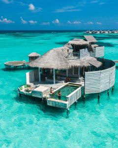 a resort in the ocean with two people in the water at Six Senses Laamu in Laamu