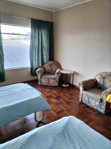 a room with two beds and two chairs and a window at Despatch Self Catering Apartments in Despatch