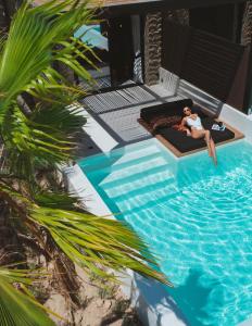 a man laying on a bed next to a swimming pool at Ftelia Black Villas in Ftelia