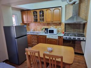 a kitchen with a wooden table and a black refrigerator at Solaris Guest House in Shkodër