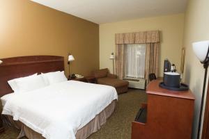 Hampton Inn Oneonta في أونيونتا: غرفه فندقيه بسرير وكرسي