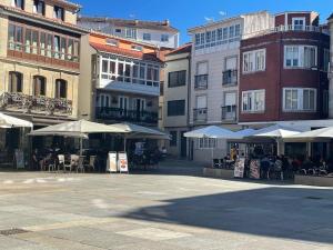 un groupe de bâtiments avec tables et parapluies dans l'établissement Apartamento Son con plaza de garaje - Galicia, à Porto do Son