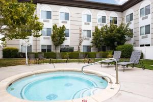 a swimming pool with chairs and a building at Hampton Inn & Suites Salt Lake City Airport in Salt Lake City