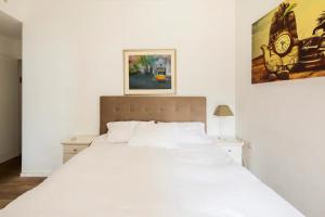 Luxury Oasis Tel Aviv Beach في تل أبيب: غرفة نوم بسرير ابيض وصورة على الحائط