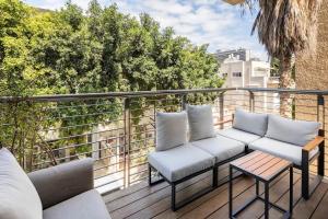 Luxury Oasis Tel Aviv Beach في تل أبيب: فناء به أريكتين وطاولة على شرفة