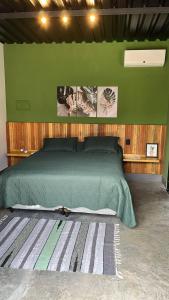 a bedroom with a green bed and a green wall at CHALÉS SÃO ROQUE in São Roque