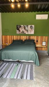ein Schlafzimmer mit einem grünen Bett und einer grünen Wand in der Unterkunft CHALÉS SÃO ROQUE in São Roque