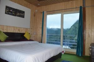 a bedroom with a bed and a large window at Himrab Chopta Resort in Chopta