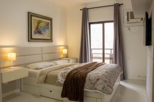 a white bedroom with a bed and a window at Luxuoso apto 3 quartos com vista p/ Praia do Forte. in Cabo Frio