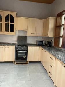 La cuisine est équipée d'armoires en bois et d'un four noir. dans l'établissement Best House Kimironko, à Kigali