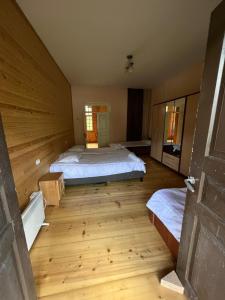 a room with two beds and a wooden floor at Mushkudiani Manor in Mestia
