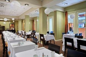 uma sala de jantar com mesas e cadeiras brancas em DoubleTree by Hilton Springfield em Springfield