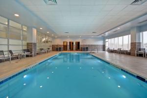 a large swimming pool with blue water in a building at Embassy Suites Syracuse in East Syracuse