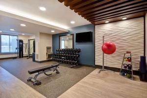 a fitness room with a gym with weights and a television at Embassy Suites Syracuse in East Syracuse