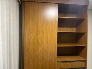 a closet with wooden shelves and a curtain at Conquista Executive Residence in Vitória da Conquista