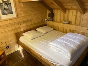 uma cama num quarto de madeira com duas almofadas em L'Ecrin des Granges - La Cime em Villarembert