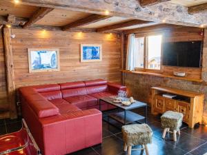 uma sala de estar com um sofá vermelho e uma televisão em L'Ecrin des Granges - La Cime em Villarembert