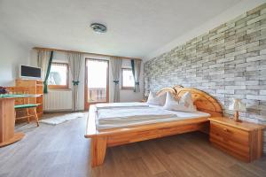 a bedroom with a wooden bed and a brick wall at Gästehaus Bliem in Ainring