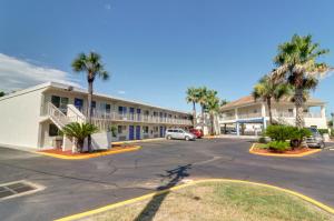 ein Parkplatz vor einem Gebäude mit Palmen in der Unterkunft Motel 6-Destin, FL in Destin