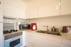 eine weiße Küche mit einer Spüle und einer Mikrowelle in der Unterkunft 2 bedrooms close to the Hilton in Tel Aviv
