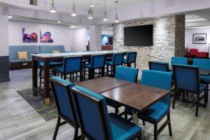 Hampton Inn by Hilton Concord/Bow في كونكورد: قاعة اجتماعات مع طاولات وكراسي وتلفزيون