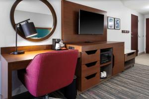 Zimmer mit einem Schreibtisch, einem TV und einem Stuhl in der Unterkunft Hampton Inn by Hilton Concord/Bow in Concord