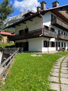 a house with a green yard in front of it at Appartamento Pelmo in San Vito di Cadore