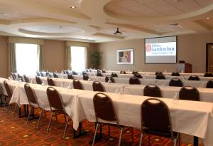 a conference room with tables and chairs and a screen at Hilton Garden Inn Atlanta/Peachtree City in Peachtree City
