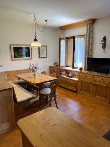 a living room with a wooden table and a television at Appartamento Pelmo in San Vito di Cadore