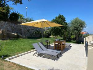 a yellow umbrella and two chairs and a table at Casa da Zéfinha - Villa, em Cinfães, no Douro in Cinfães